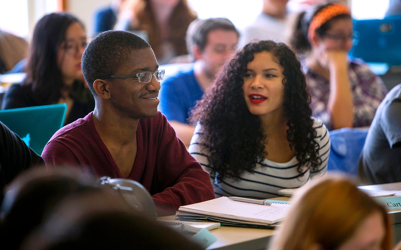 Two students smile while sitting in a CCM Music Theory and Composition classroom.