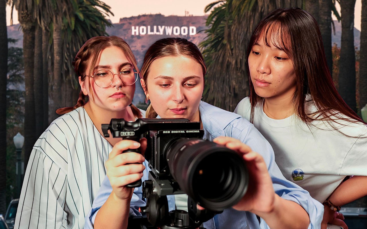 ccm-summer-in-la-2024-01.jpg Three Media Production students focus on the screen of a digital camera in front of the Hollwood sign