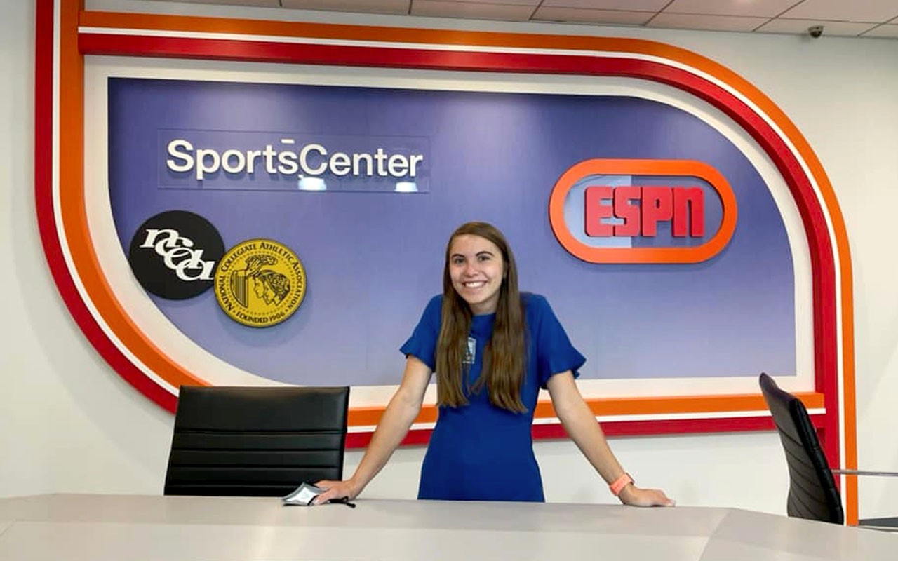ccm-sports-media-production-2024-01.jpg A Sports Media Production student stands behind a ESPN SportsCenter desk