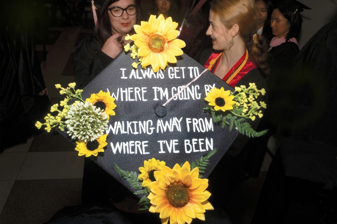 Graduation cap decorated with flowers and the words "I always get to where I'm going by walking away from where I've been."