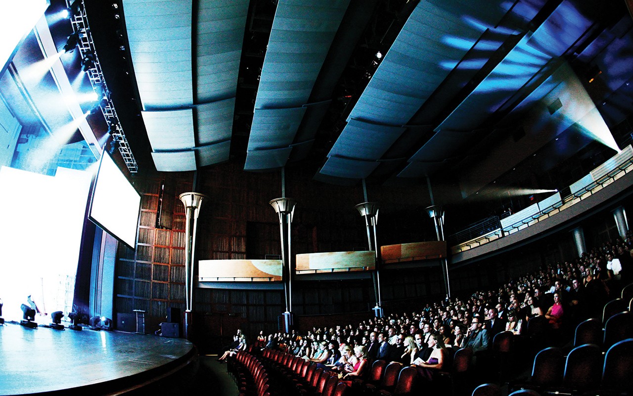 Stage lighting reveals a side view of audience sitting in Corbett Auditorium 